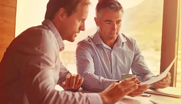 Twee mannen in gesprek in een zonnige kantoorruimte