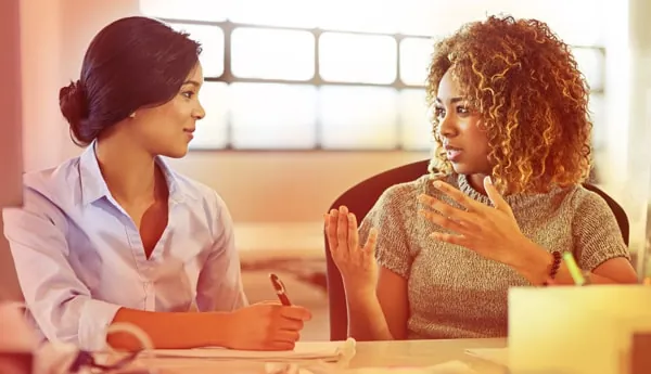 Twee vrouwen in gesprek aan een tafel