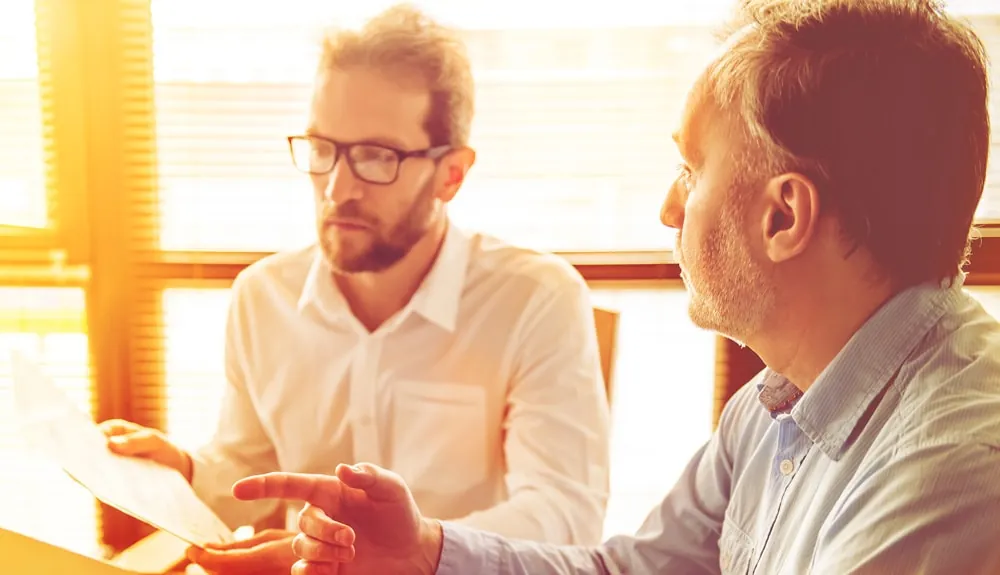 Twee mannen bespreken een plan aan tafel