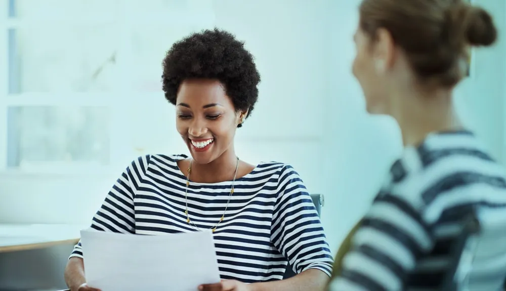 Een vrouw met een document in de hand in gesprek met een collega